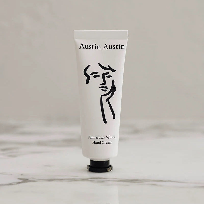 White hand cream tube with black logo and text on a light gray background