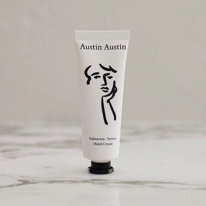 White hand cream tube with black logo and text on a light gray background