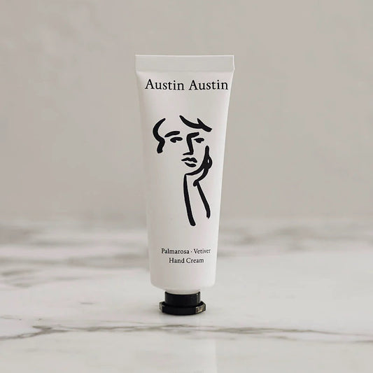 White hand cream tube with black logo and text on a light gray background