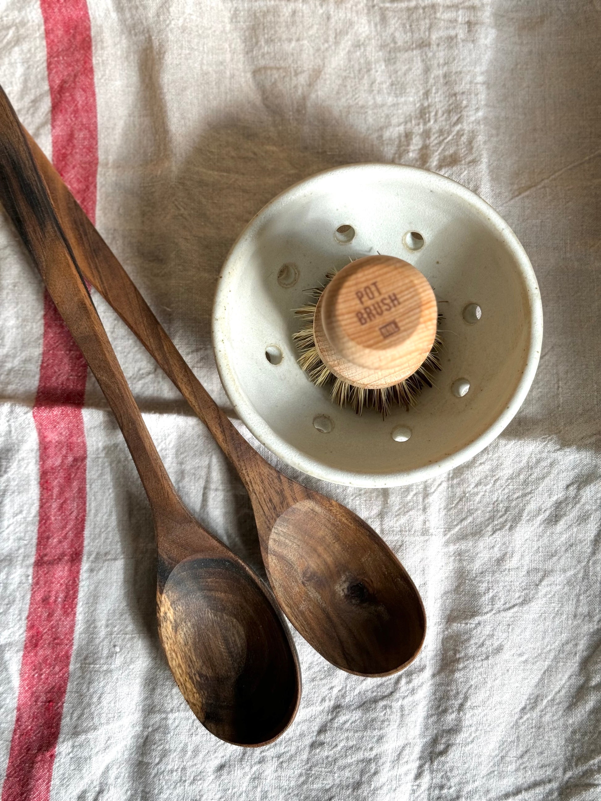 Wooden pot brush in handmade ceramic colander with hand carved wooden spoons